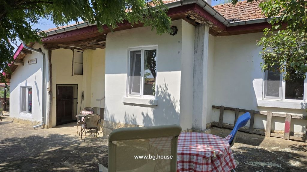 Property photo 1 of 100 Outdoor Courtyard Showing White Plaster Walls, Tiled Roof, And A Small Table With Chairs Under Tree Shade.