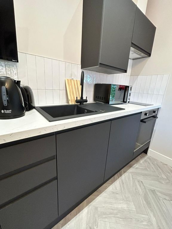 Property photo 3 of 7 Modern Kitchen With Sleek Dark Cabinetry, A Black ...