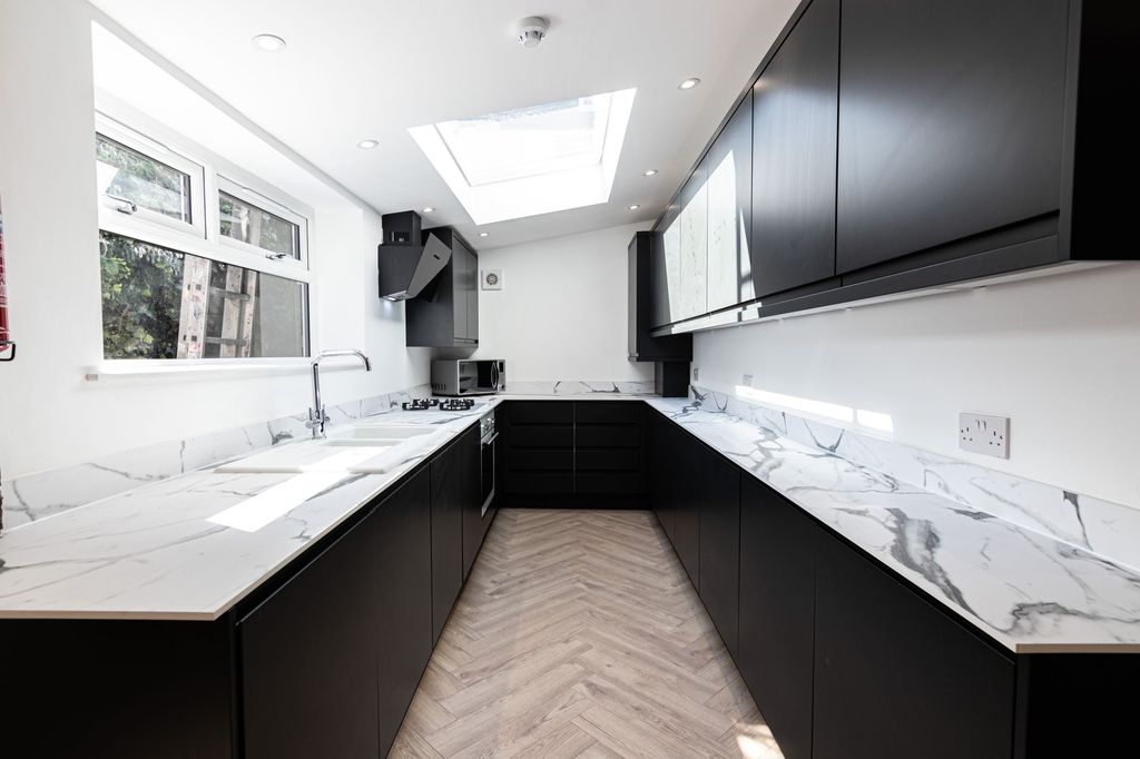 Property photo 3 of 6 Modern And Sleek Kitchen Featuring Black Cabinets,...