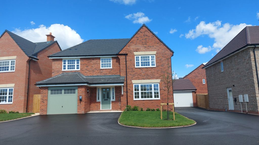 Property photo 1 of 10 A Modern Brick House With A Green Garage Door Sits On A Paved Driveway In Front Of A Bright Blue Sky