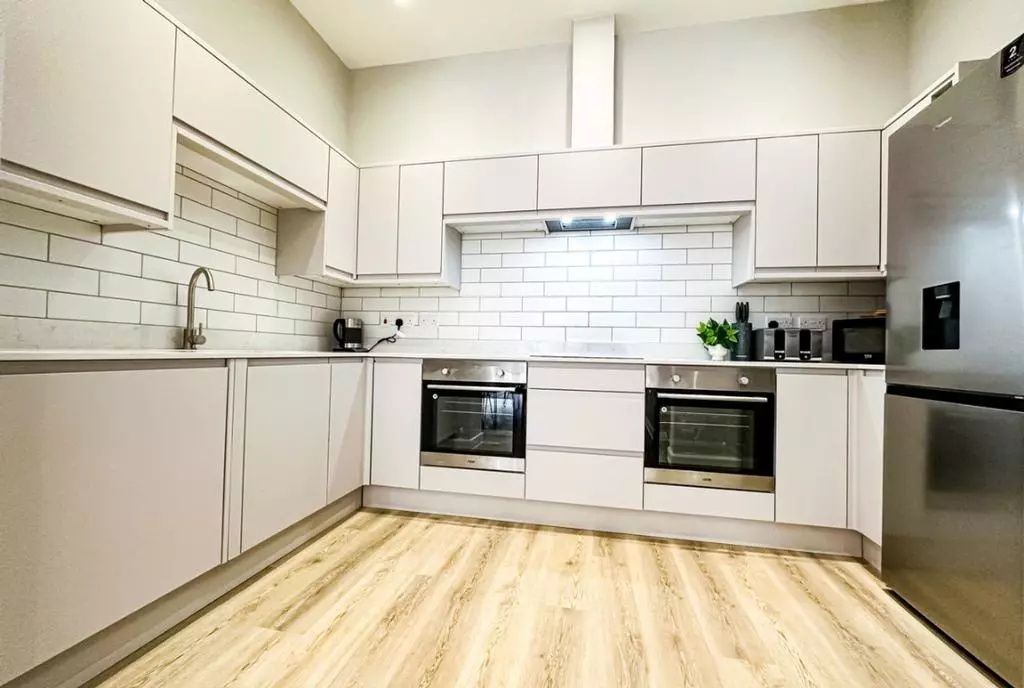 Property photo 3 of 6 Bright And Modern Kitchen Featuring Sleek White Ca...