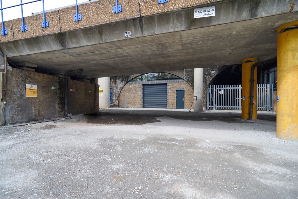 Property photo 3 of 5 The Front Of An Arch, Which Has A Front Yard And Sits Behind Metal Fencing. The Arch Has A Closed Electric Roller Shutter Entrance Large Enough For Vehicle Access.