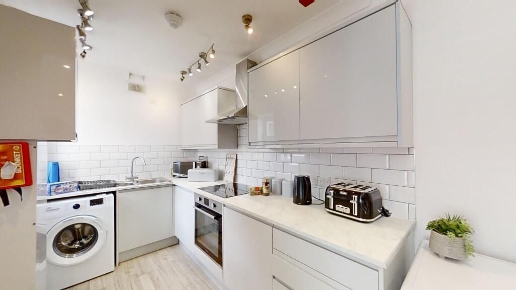 Property photo 1 of 12 Bright And Modern Kitchen Featuring Sleek White Ca...