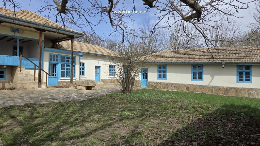 Property photo 2 of 100 Stone Paved Courtyard With Grass Patches And Traditional House Walls Featuring Blue Framed Windows And Doors.