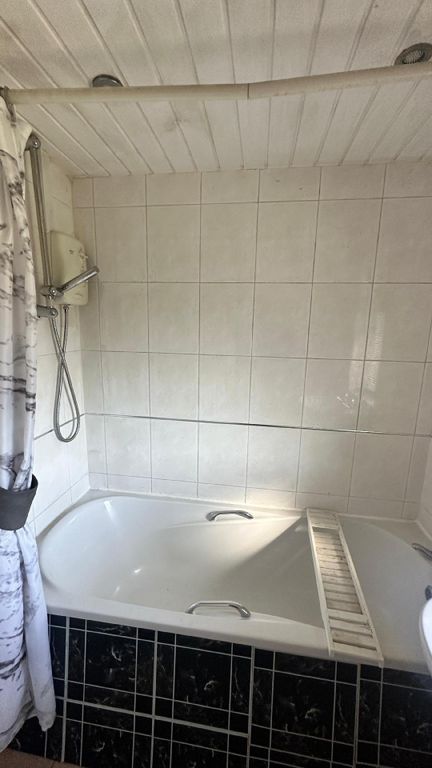 Property photo 3 of 7 A Clean Bathroom Featuring A Bathtub With A Shower...