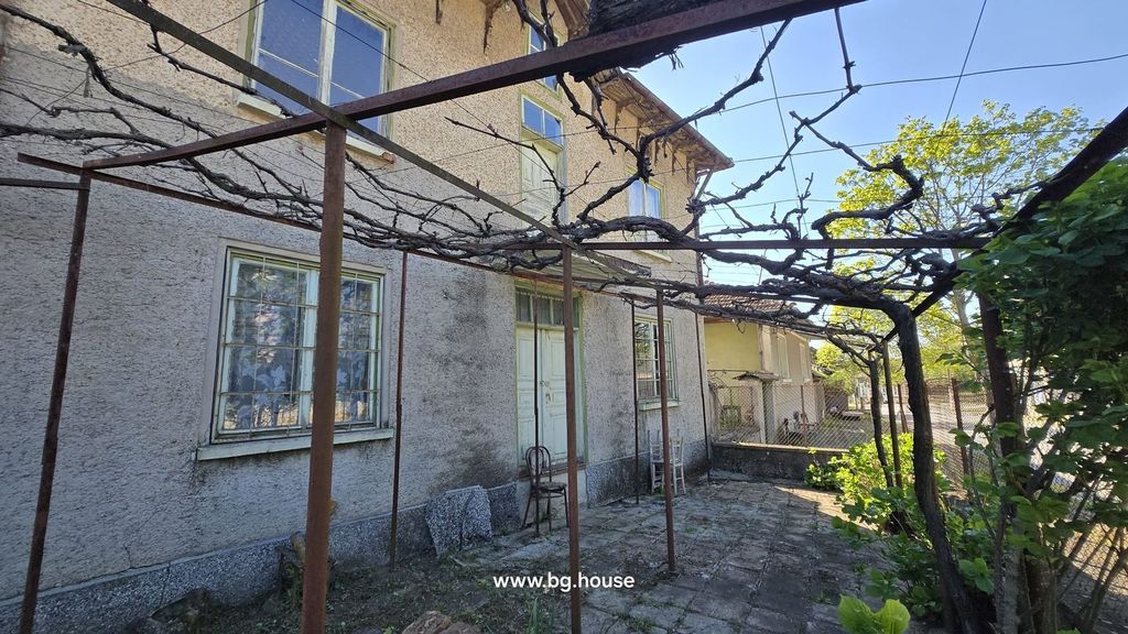 Property photo 3 of 37 Side Wall Of The House Featuring Windows, A Wooden Door, And A Metal Trellis With Bare Vines.