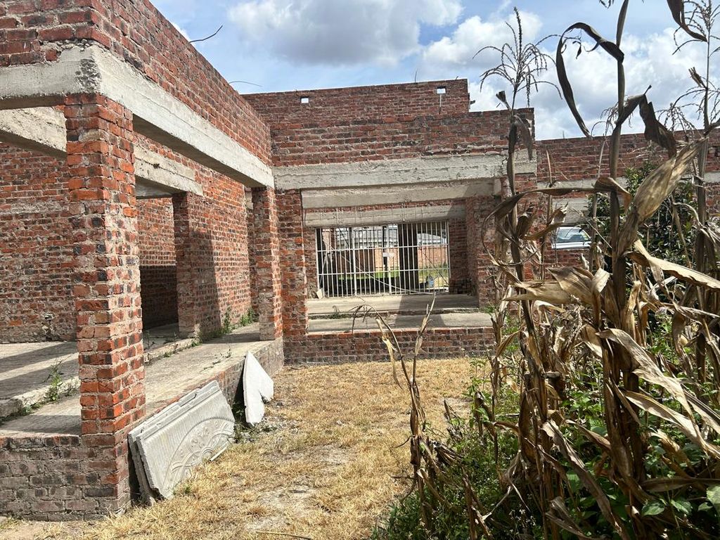 Property photo 3 of 8 Abandoned Brick Building With Concrete Beams And Arched Openings, A Gated Passage In The Center, And Dry Plants In The Foreground.