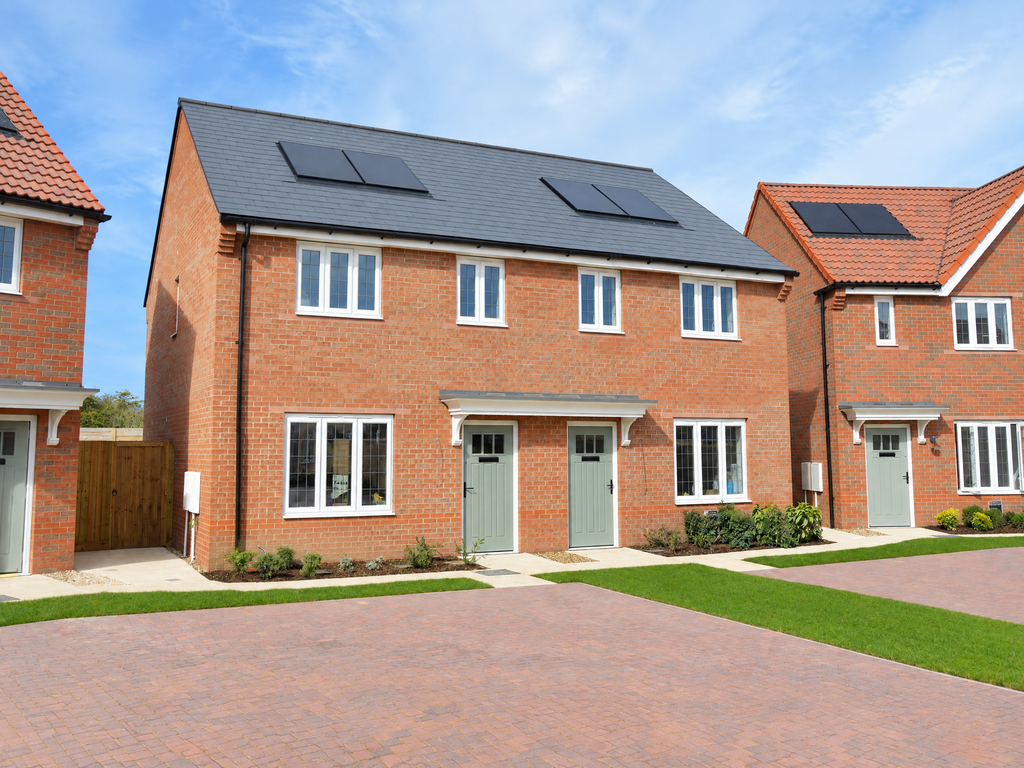 Property photo 1 of 10 A Red-Brick House With Solar Panels Stands Behind A Paved Driveway And Green Lawns Under A Clear Blu