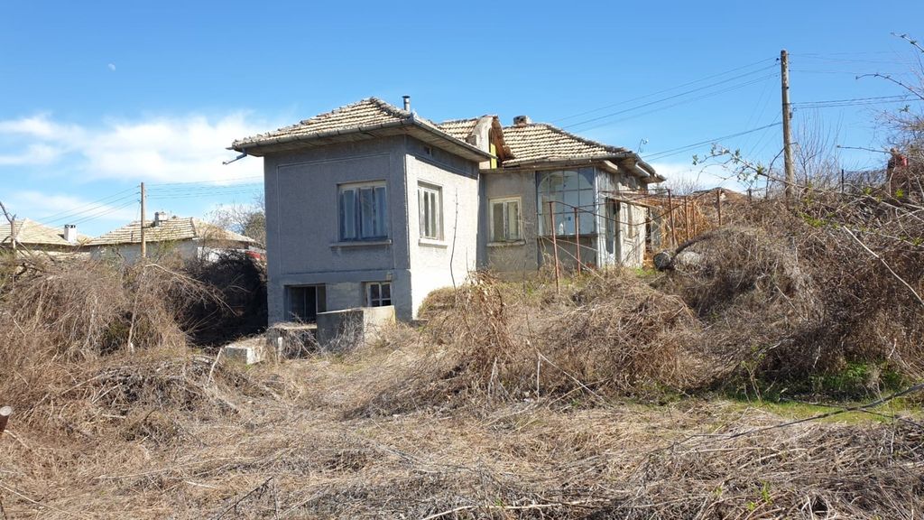 Property photo 1 of 33 Exterior View Of A Traditional Bulgarian Village House With A Tiled Roof And Grey Walls, Surrounded By Dry Bushes And Grass Under A Clear Blue Sky.