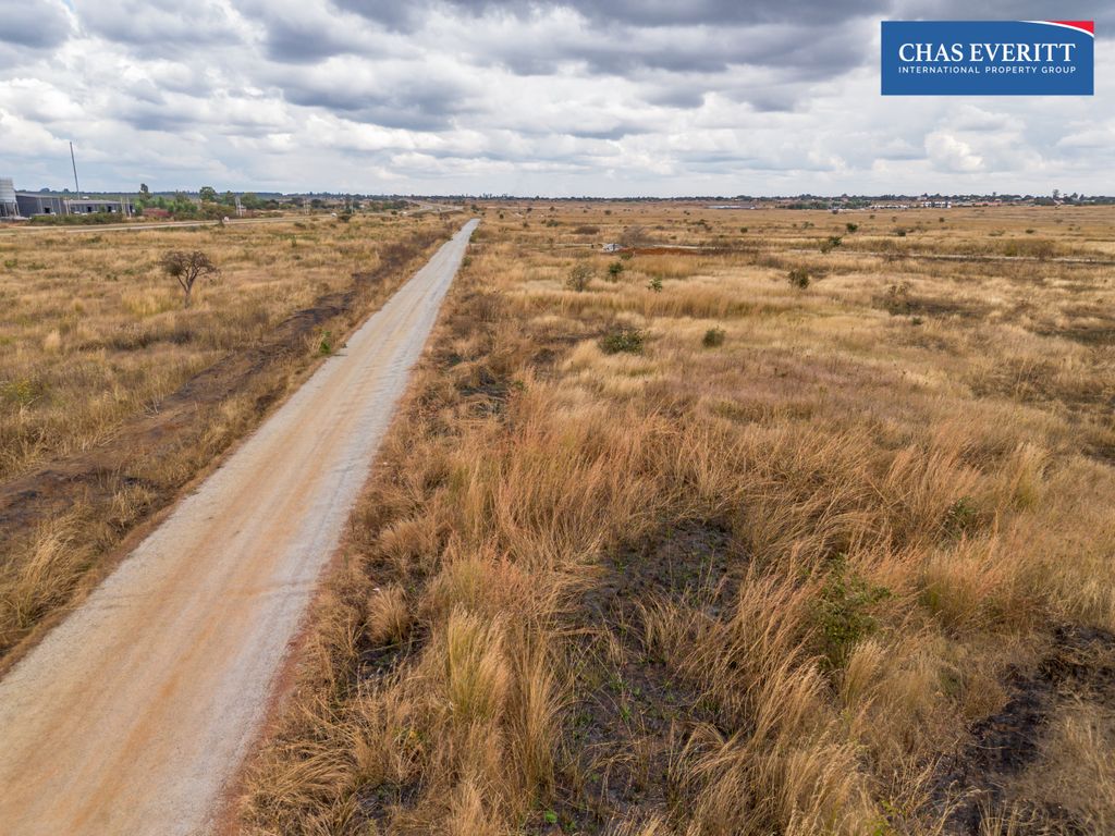 Property photo 1 of 10 Dusty Dirt Road Cuts Through A Dry Grassy Field Toward The Horizon Under Stormy Clouds; Chas Everitt Logo In The Top-Right Corner.