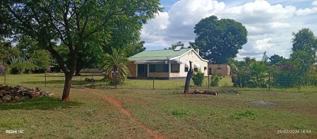 Property photo 1 of 12 Single-Story House With A Green Roof In A Rural Yard, Surrounded By A Wire Fence, Trees, And A Dirt Path In The Foreground.