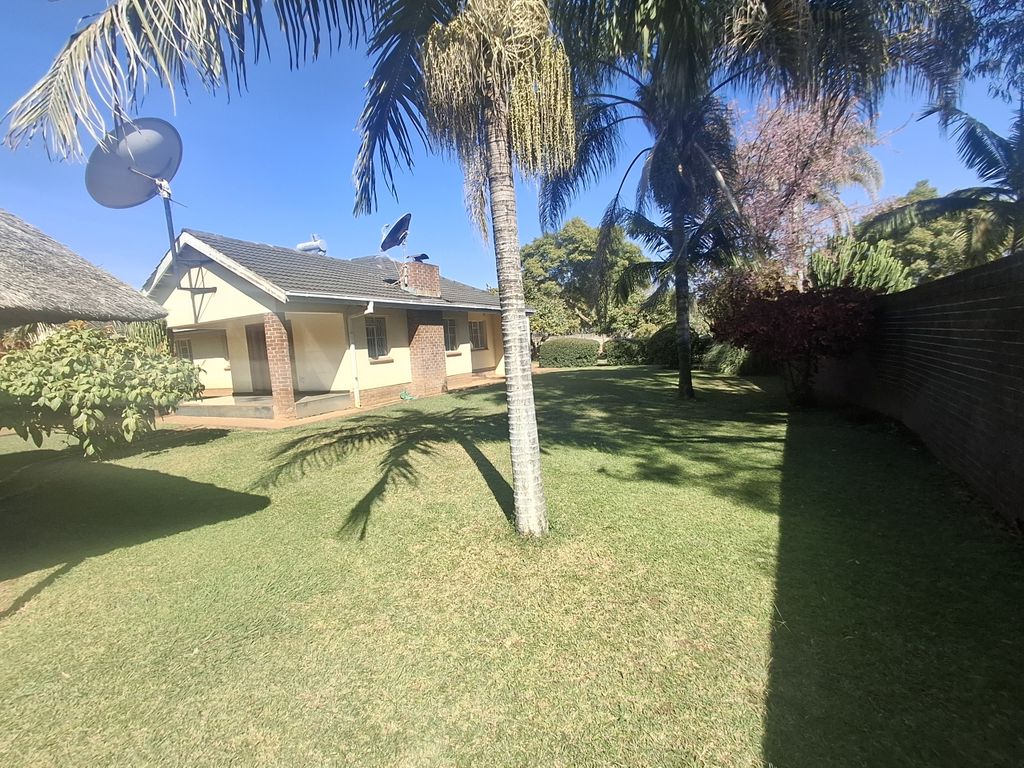 Property photo 2 of 14 Sunny Suburban Backyard With Palm Trees, A Neatly Mowed Lawn, And A Single-Story House With Satellite Dishes On The Roof On A Clear Day.