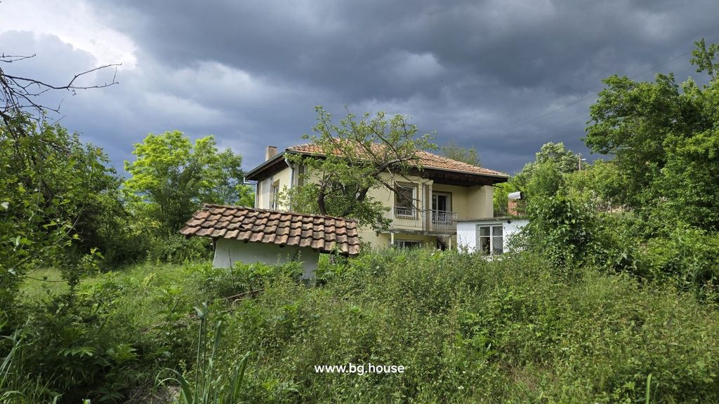 Property photo 3 of 29 View Of The Yellow Two-Storey House With A Balcony, Surrounded By Dense Green Vegetation And A Cloudy Sky.
