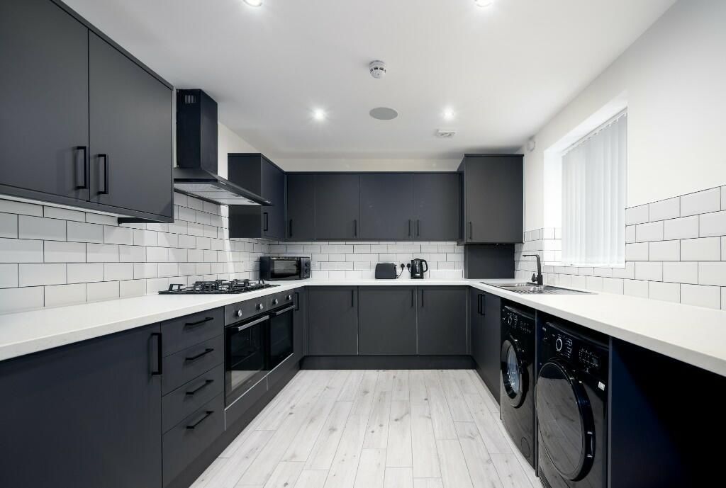 Property photo 3 of 6 Modern And Stylish Kitchen Featuring Sleek Dark Ca...