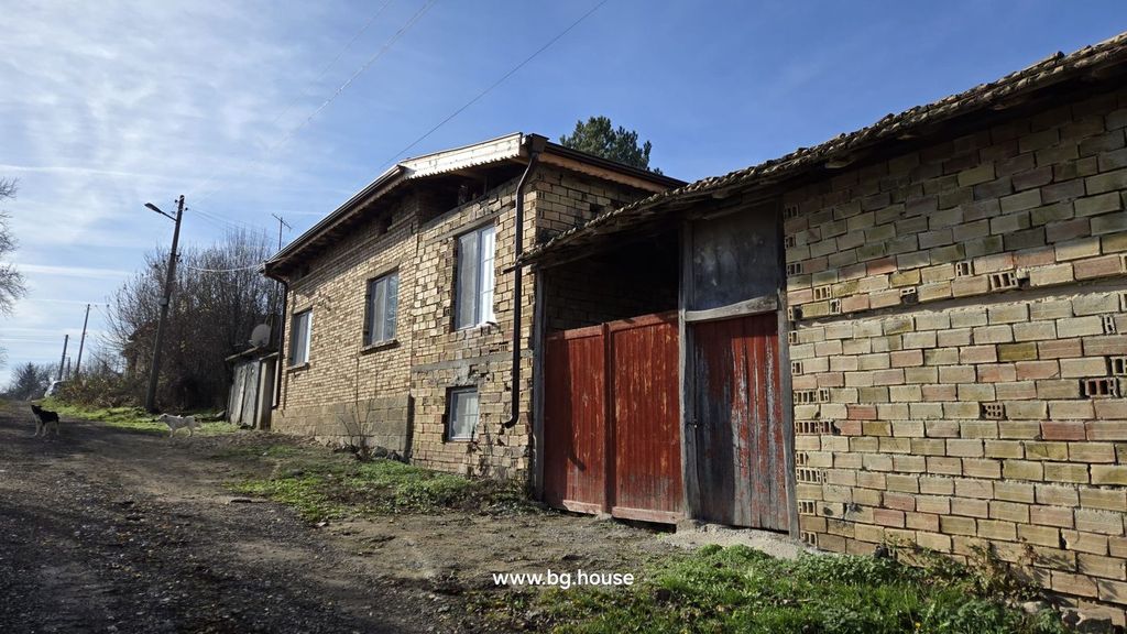 Property photo 1 of 79 Exterior View Of A Brick House With A Red Wooden Gate And Two Dogs On The Dirt Road Beside It.