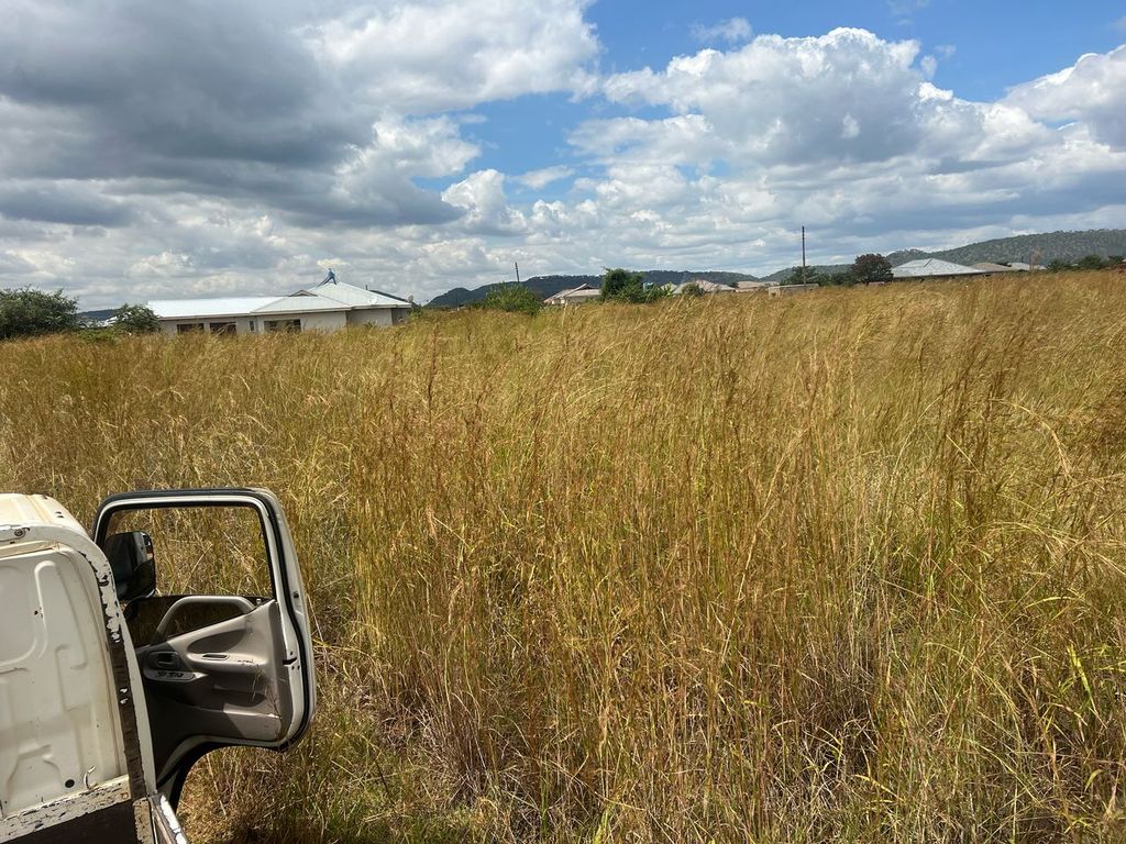Property photo 3 of 4 White Pickup With The Driver Door Open Sits In A Tall, Dry Grassy Field, With Houses And Low Hills In The Distance Under A Cloudy Blue Sky.