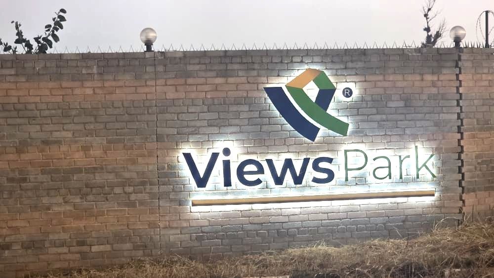 Property photo 1 of 7 Brick Wall With An Illuminated 'views Park' Sign And A Colorful Geometric Logo, Lit From Below At Dusk.