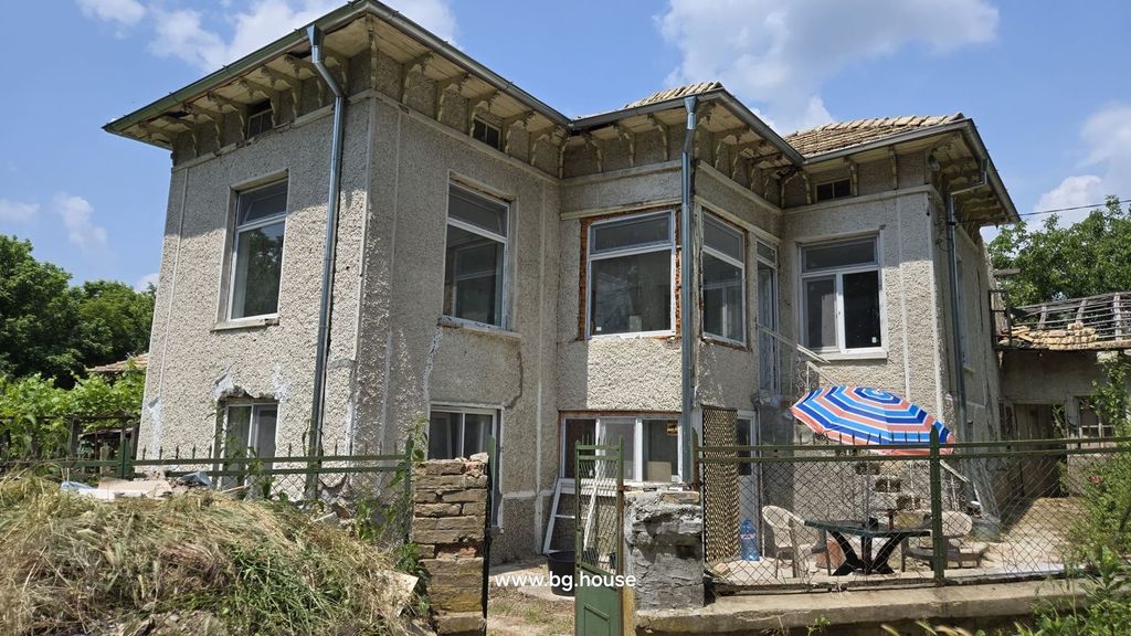 Property photo 2 of 40 Side Perspective Of The Bulgarian House Highlighting The Textured Walls, Windows, And Fenced Yard With Table And Chairs Under A Striped Umbrella