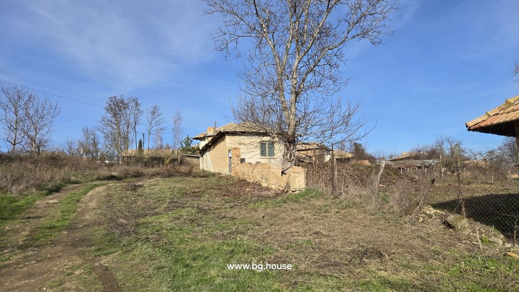 Property photo 2 of 54 A Dirt Road Runs Beside A Small Brick House With A Leafless Tree Nearby, Set In A Rural Landscape Under A Clear Blue Sky.