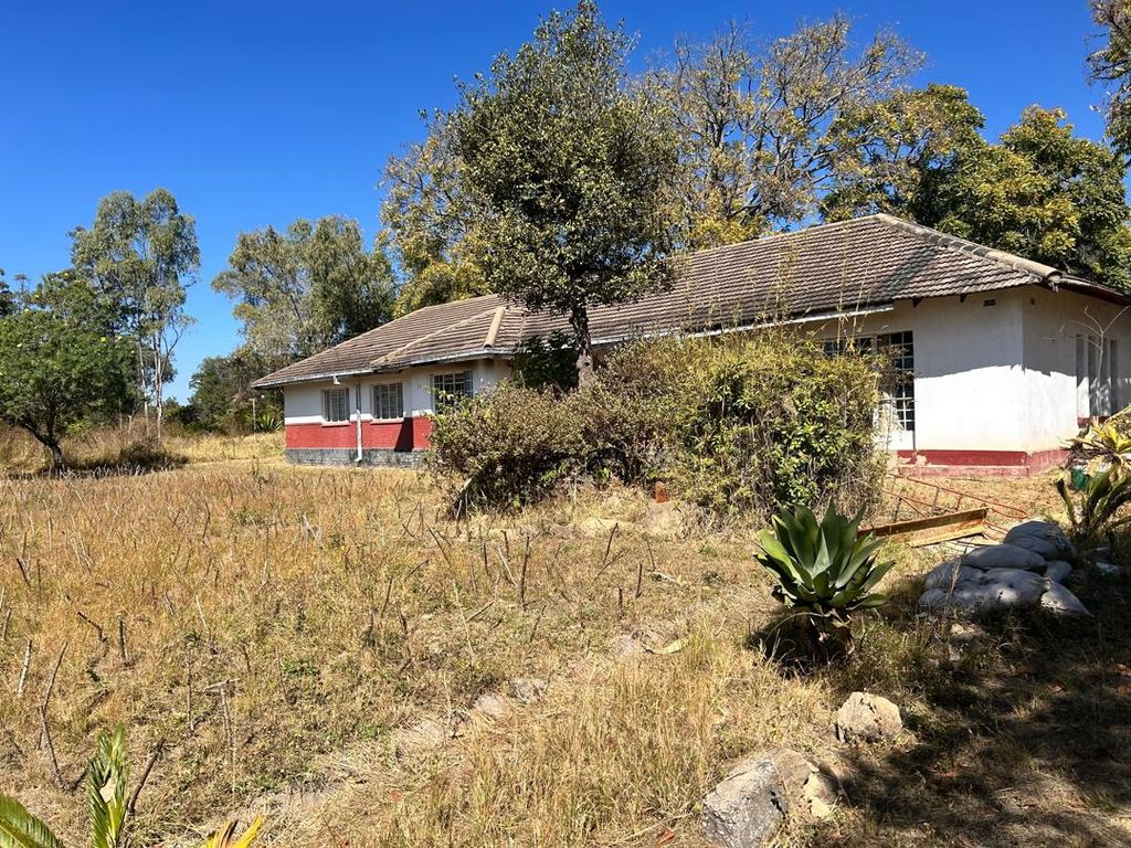 Property photo 2 of 9 Single-Story White House With A Red Foundation In A Dry Grassy Yard Under A Bright Blue Sky.