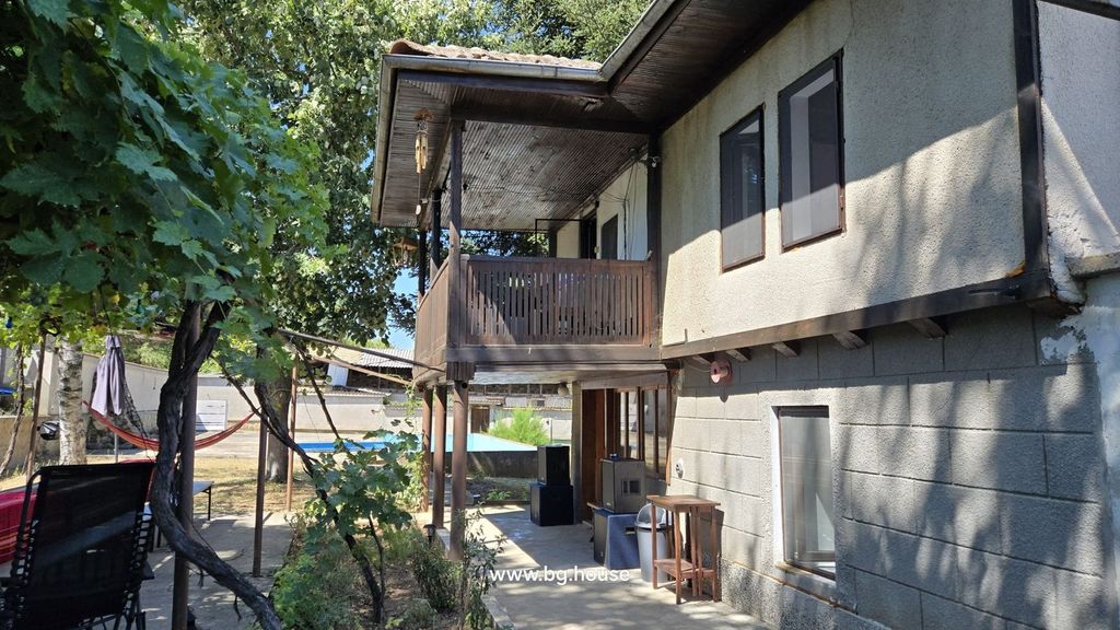 Property photo 2 of 100 Side Perspective Of The House Showing A Wooden Balcony Above A Shaded Garden Area Furnished With Tables And Chairs.