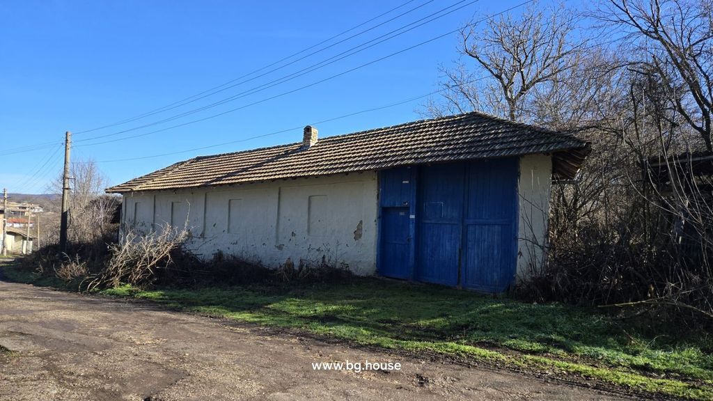 Property photo 3 of 54 Side View Of A White Outbuilding Featuring Large Blue Wooden Doors And A Tiled Roof Next To A Dirt Road.