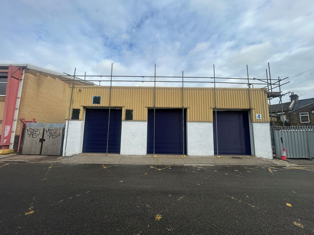 Property photo 1 of 1 The Front Of A Warehouse Unit, With An Open Electric Roller Shutter Entrance Big Enough For Vehicle Access, And A Pedestrian Door.