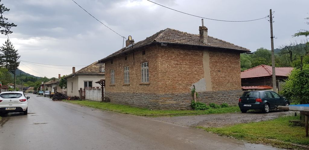 Property photo 2 of 100 Exterior Corner View Of A Brick House With Tiled Roof Located On A Village Street With Parked Cars And Neighboring Houses.