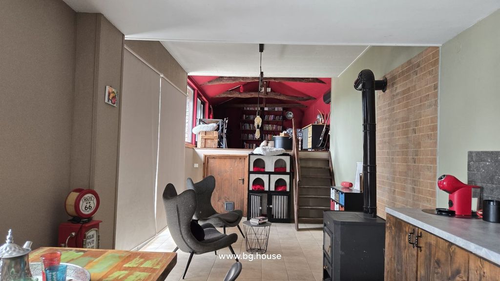 Property photo 3 of 100 Interior Living Space Showing Two Modern Chairs, A Wood Stove, And Exposed Red Ceiling Beams With Bookshelves In The Background.