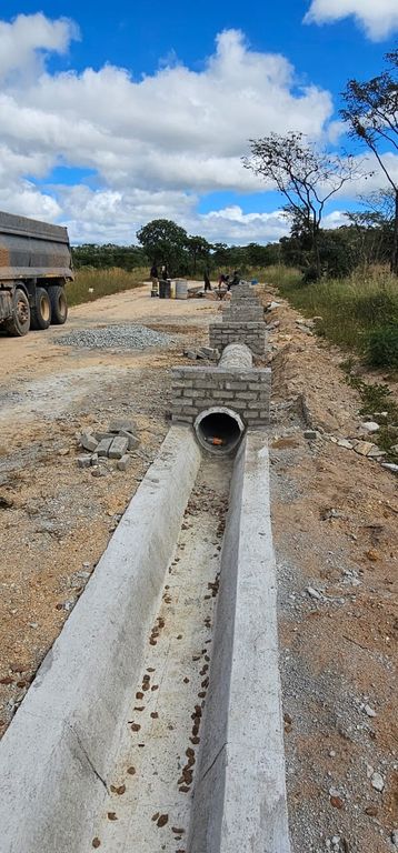 Property photo 2 of 2 Concrete Drainage Trench With A Circular Pipe Outlet Under Construction; Bricks Stacked Nearby And A Truck On A Dirt Road In The Background.