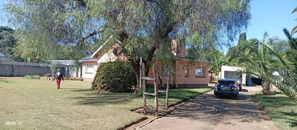 Property photo 2 of 25 Person Walking On A Lawn Toward A Peach-Colored House With A Large Tree In Front; A Driveway With A Blue Car Nearby.