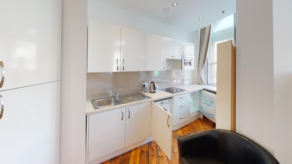 Property photo 2 of 6 Bright And Modern Kitchen Featuring Sleek White Ca...