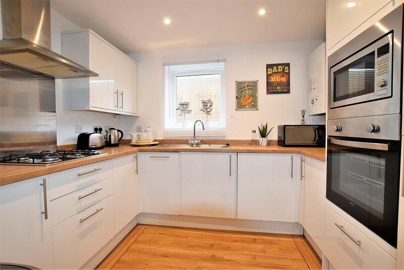 Property photo 1 of 7 Bright And Modern Kitchen Featuring Sleek White Ca...