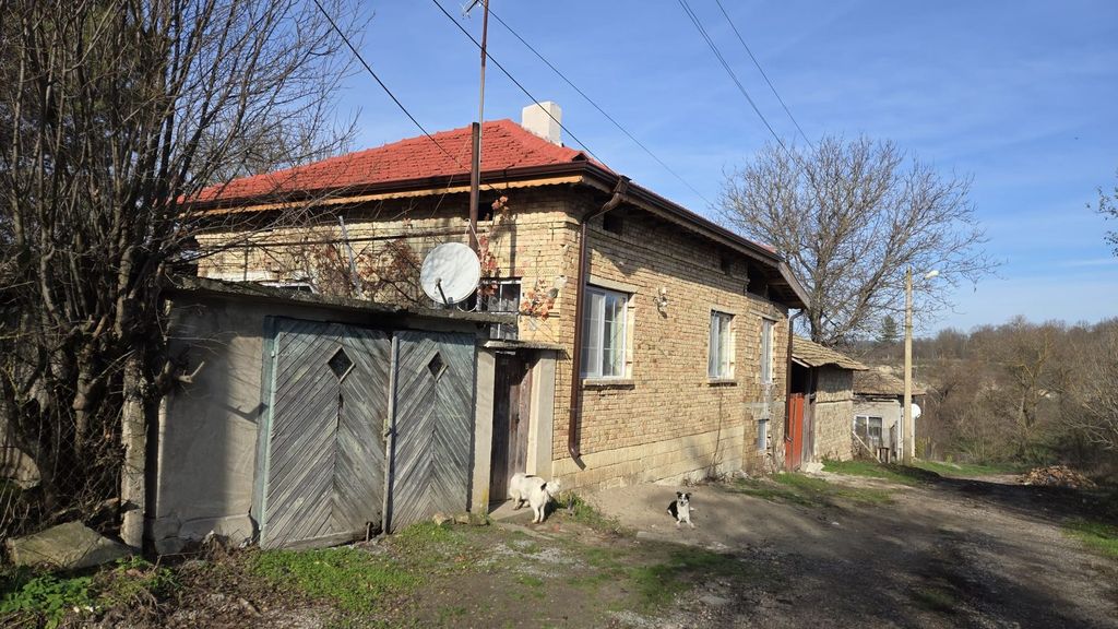 Property photo 3 of 79 Side View Of A Brick House With A Red Roof And Wooden Garage Doors, With Dogs Near The Entrance.