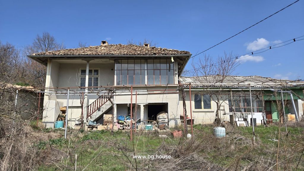 Property photo 2 of 52 Front Facade Of A Two-Storey Bulgarian House Showing External Stairs And Storage Area Beneath, With Dry Grass In The Foreground