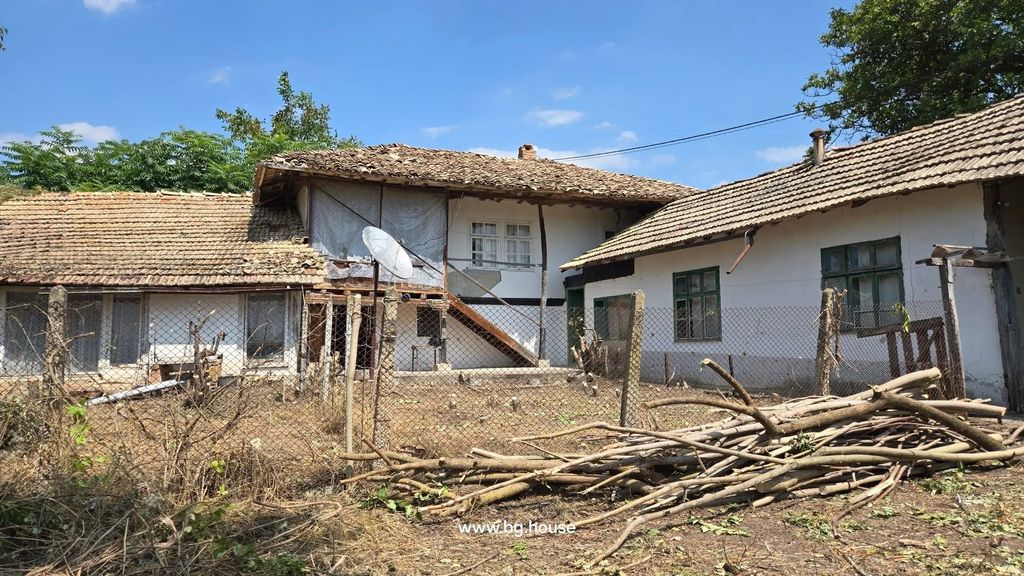 Property photo 1 of 75 View Of A Traditional Bulgarian House With Annexes, Tiled Roofs, Wooden Stairs, And A Fenced Yard With Dry Branches And Sparse Vegetation Under A Clear Blue Sky.