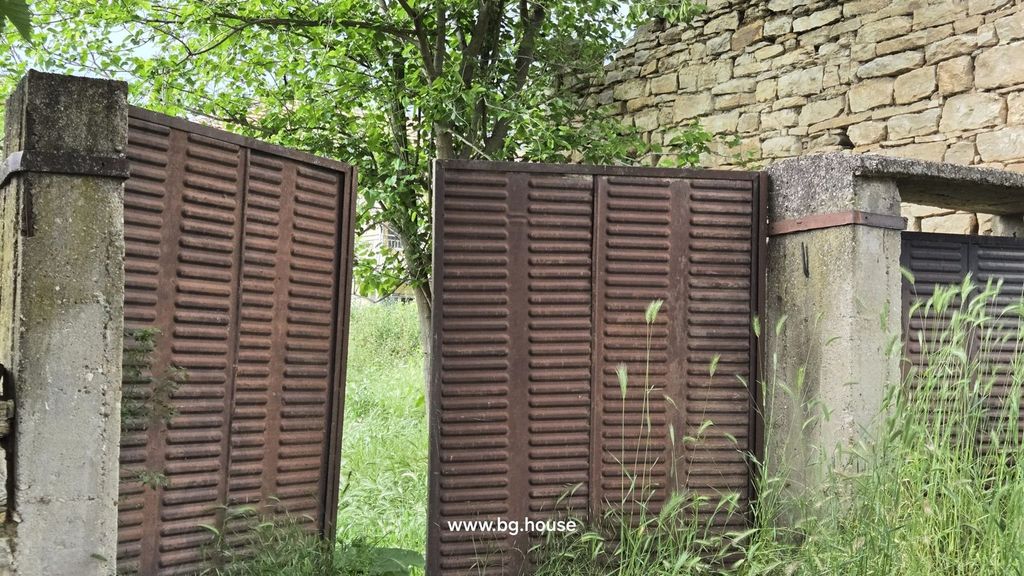 Property photo 2 of 29 Close-Up Of A Rusty Metal Gate Next To A Stone Wall With Green Plants Growing Around It.