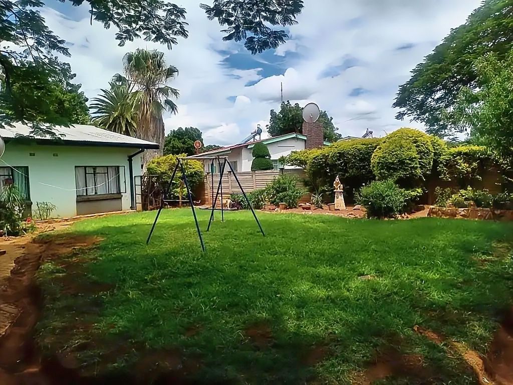 Property photo 2 of 17 Backyard With A Metal Swing Set On A Green Lawn, A Pale House On The Left, And Trimmed Hedges Along A Fence On The Right Under A Blue Sky.