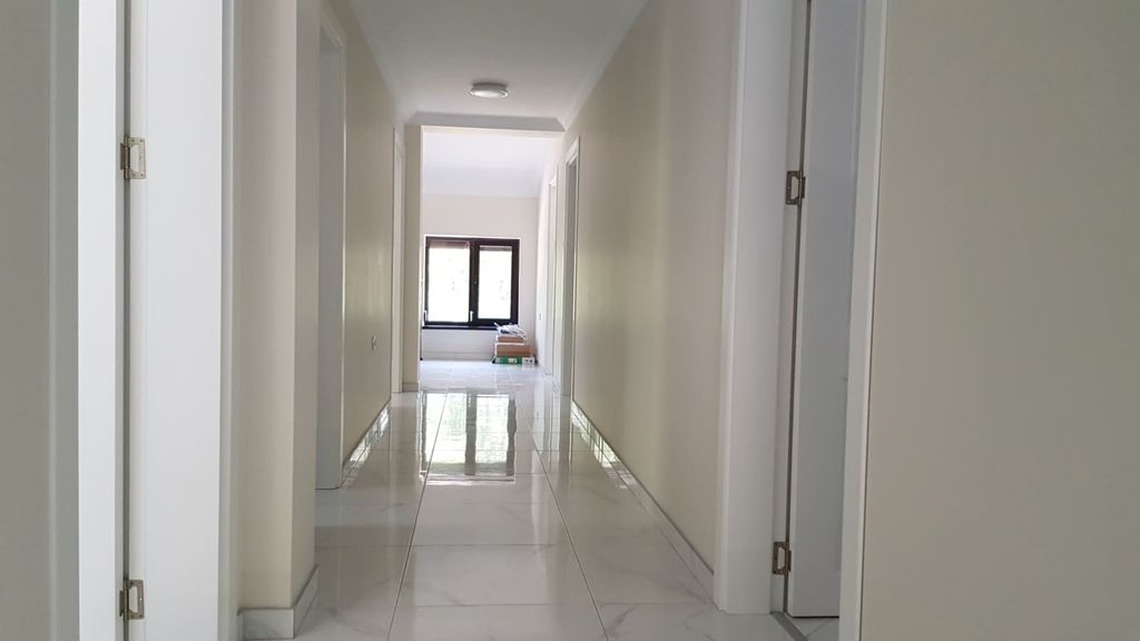 Property photo 3 of 69 Bright Indoor Corridor With White Walls, Multiple Doors, And Window At End