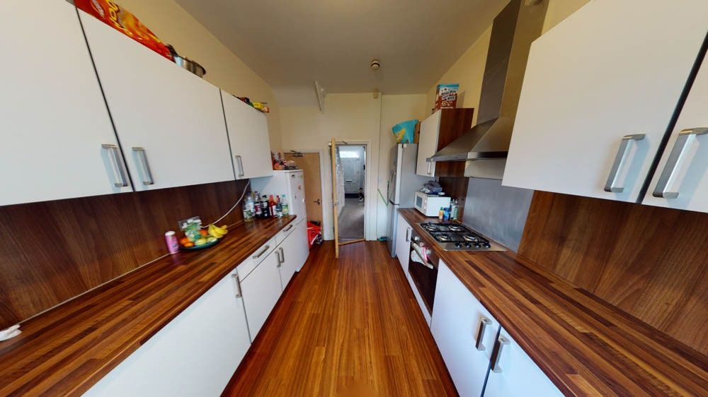 Property photo 2 of 8 A Long, Modern Kitchen Featuring White Cabinetry c...