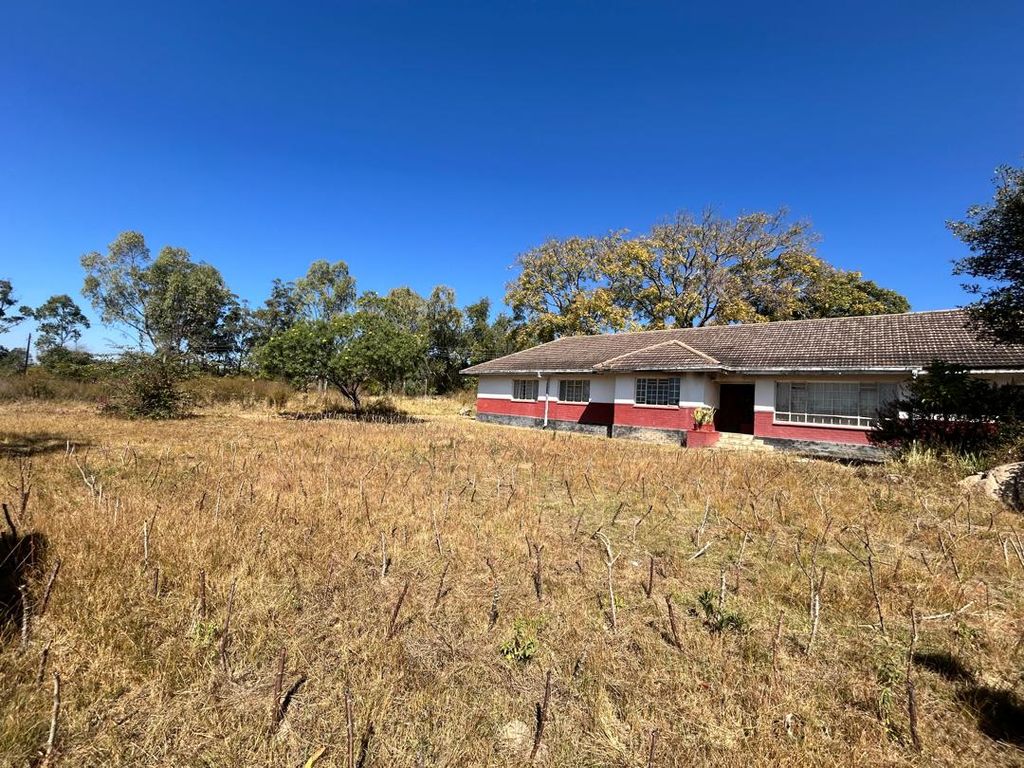 Property photo 1 of 9 Single-Story House With A Red And White Exterior In A Dry, Grassy Field Under A Bright Blue Sky.