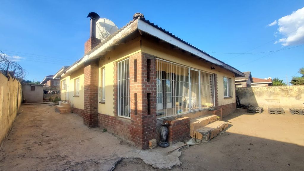Property photo 1 of 7 Single-Story House With Yellow Walls And Brick Accents, Gated Front Porch, And A Dirt Yard With Construction Blocks Nearby