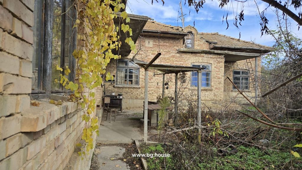 Property photo 2 of 53 Side Perspective Of The Brick House Showing Windows, A Covered Porch, And Surrounding Overgrown Garden Plants