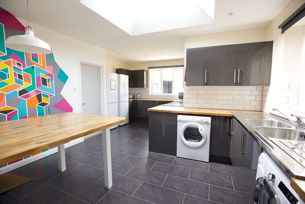 Property photo 3 of 6 Bright And Modern Kitchen Featuring Sleek Dark Cab...