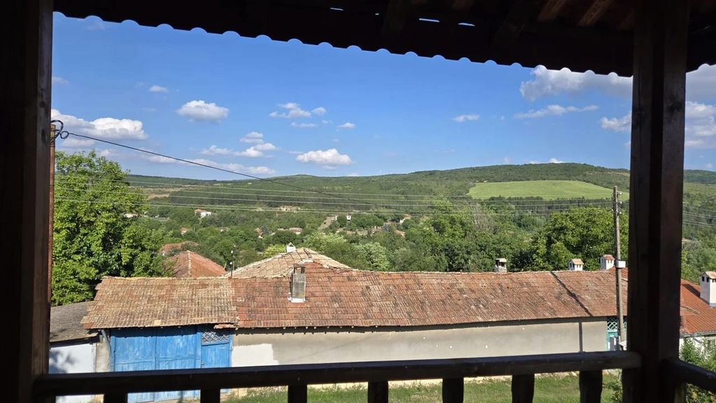 Property photo 3 of 60 View From A Covered Wooden Balcony Overlooking Village Rooftops And Green Hills Under A Partly Cloudy Blue Sky.