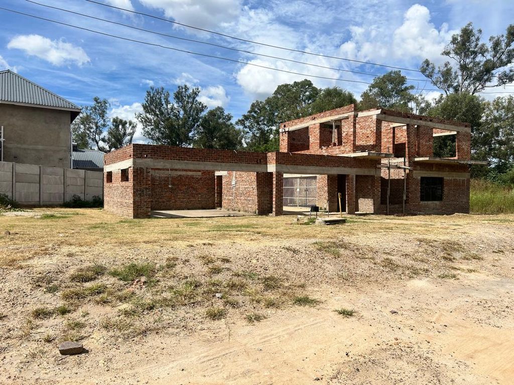 Property photo 1 of 8 Brick, Two-Story House Under Construction With Exposed Walls And Scaffolding In A Dusty Yard Against A Blue Sky.