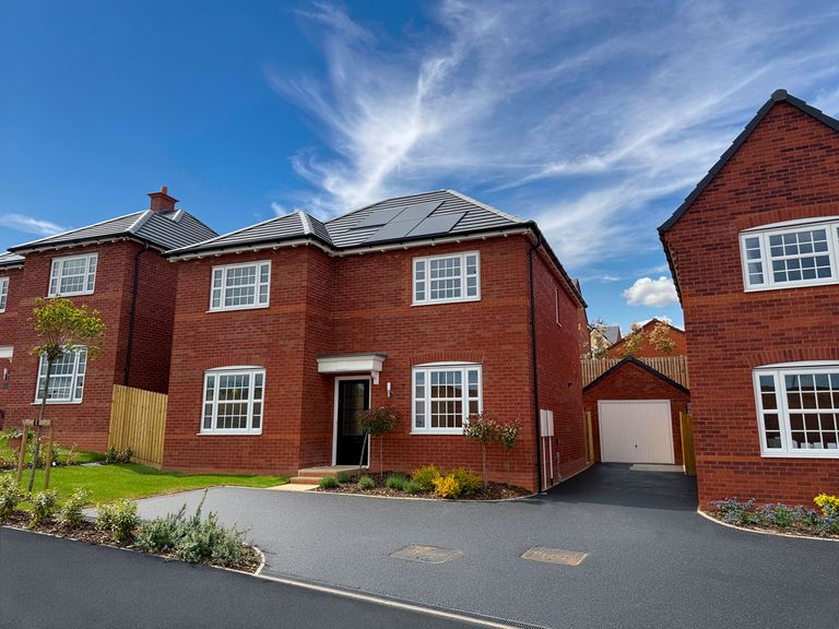 Property 1 of 10. A Newly Built Red Brick House With A Paved Driveway And Garage Sits Under A Bright Blue Sky With Wis